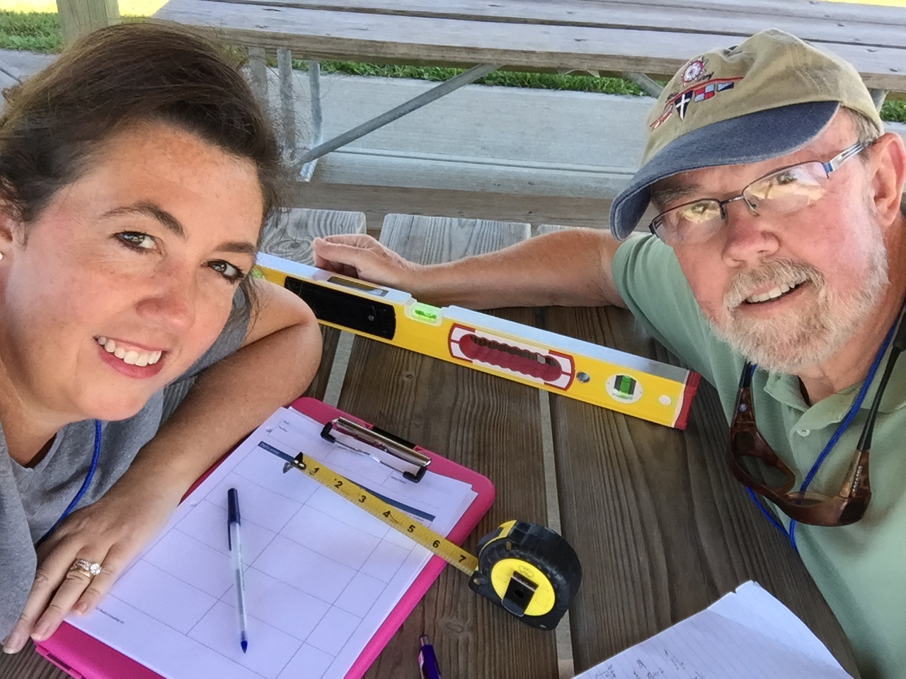 Jennifer Skulski and Rich Bowerman take a selfie with digital level, tape measure and clip board.