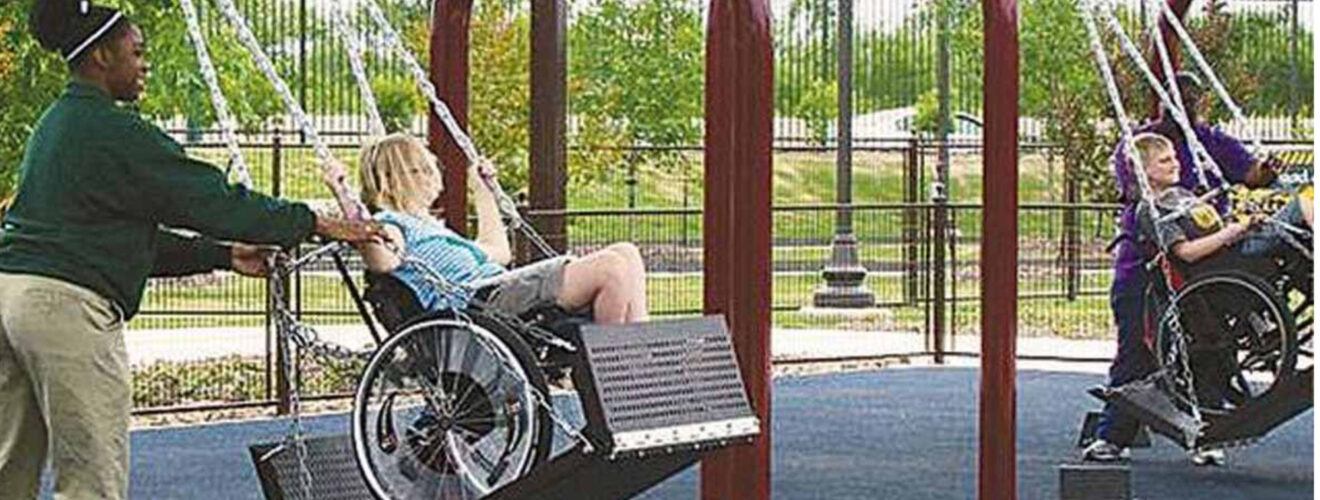 Child in wheelchair being pushed on metal platform swing. Words stricken share if you think this belongs in all parks. Replaced with Nope. Not a good idea. Read more about why.